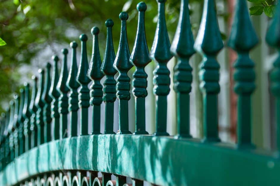 Wrought iron corner post joining two fence panels at an angle