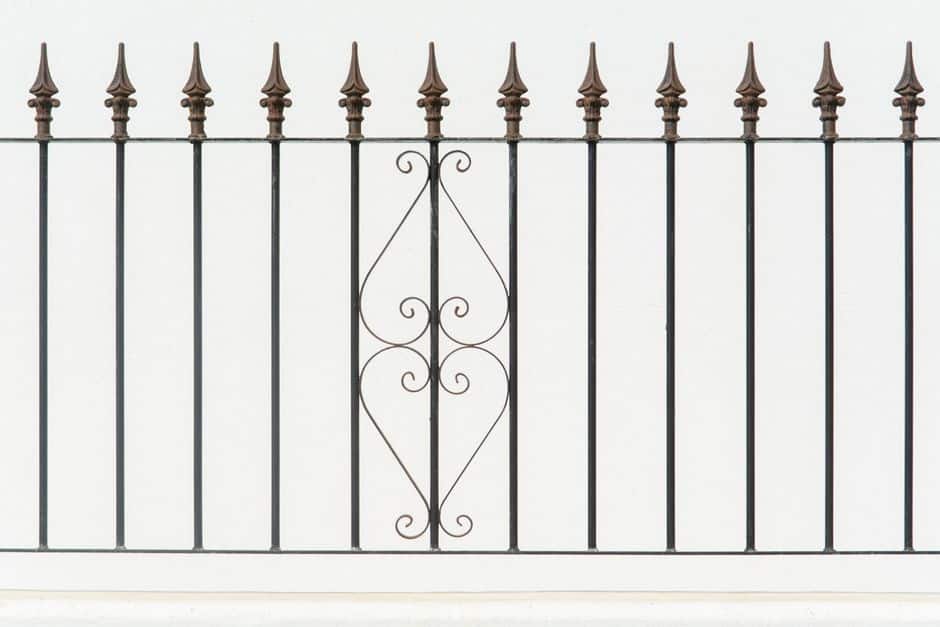 Row of wrought iron fence posts topped with spear-point finials