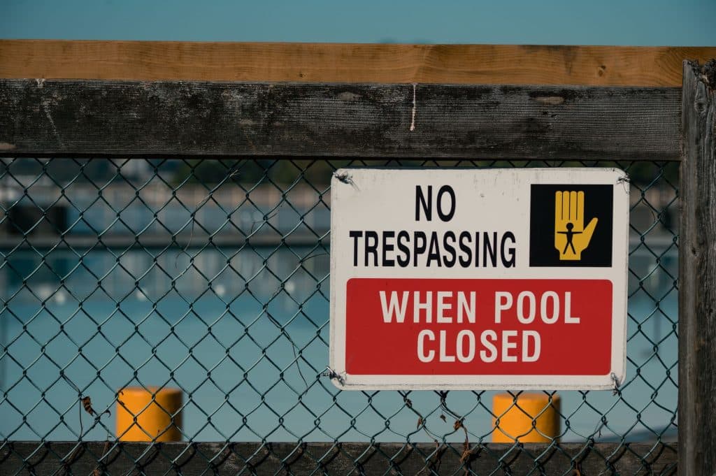 Tape measure showing pool fence height against an aluminum fence panel