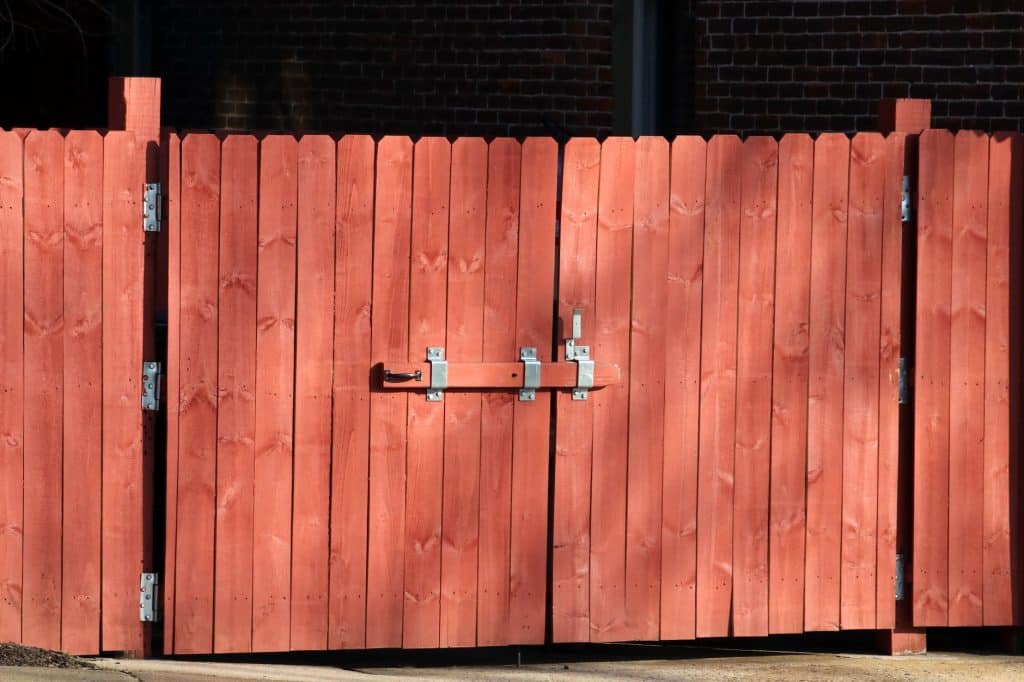 Close-up of a self-closing aluminum gate hinge and latch on a pool fence