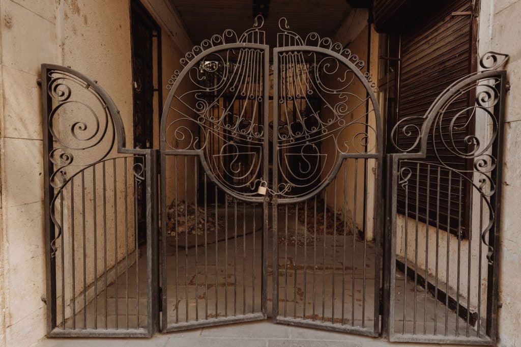 Spear-top wrought iron picket fence with scrollwork gate outside a Garden District home